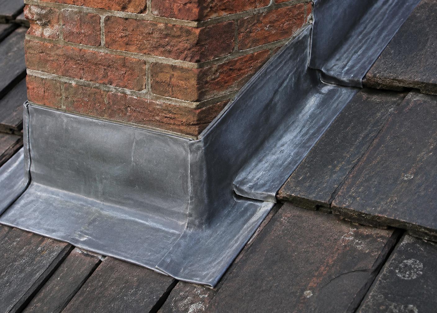 Detail van loodwerk en waterdichting rond een schoorsteen